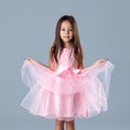 Cute little girl in pink princess dress on gray background. Royalty Free Stock Photo