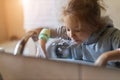 Cute little child girl rinses her mouth with water, looking at mirror and spits water into the sink