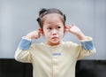 Cute little child girl shutting down her ears, holding her hands covers ears not to hear