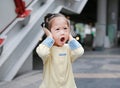 Cute little child girl shutting down her ears, holding her hands covers ears not to hear