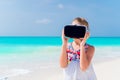 Cute little child girl using VR virtual reality goggles. Adorable girl look into the virtual glasses on white beach Royalty Free Stock Photo