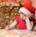 Cute little child girl writes the letter to Santa Claus near Christmas tree indoors.Merry Christmas and Happy Holidays Royalty Free Stock Photo