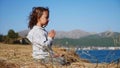 Cute little child gurl meditating alone in lotus pose at lake shore