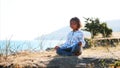 Cute little child gurl meditating alone in lotus pose at lake shore