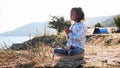 Cute little child gurl meditating alone in lotus pose at lake shore