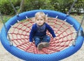 Cute little child having fun on a colorful swing outdoor in the park. Beautiful spring day in children playground Royalty Free Stock Photo