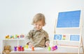 Cute little child having fun at home playing with colorful stamps on paper. Indoor activity for kids