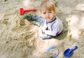 Cute little child having fun playing with sand and colorful toys in the park, beautiful summer sunny day in children playground. Royalty Free Stock Photo