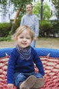 Cute little child with his mother having fun on a colorful swing outdoor in the park. Beautiful spring day in children playground Royalty Free Stock Photo