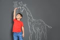 Cute little child measuring height near chalk giraffe drawing