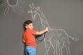 Cute little child playing doctor with chalk giraffe drawing on grey Royalty Free Stock Photo