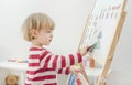 Cute little child playing at a magnetic board, learning letters, numbers and geometric shapes at home. Educative and funny indoor