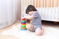 Cute little child playing nesting blocks at home