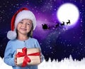 Cute little child and Santa Claus flying in his sleigh against moon sky on background. Christmas celebration Royalty Free Stock Photo