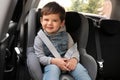 Little child sitting in safety seat inside car. Danger prevention