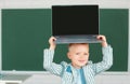 Cute little child using laptop computer, kid boy holding laptop on head. Little funny system administrator. Royalty Free Stock Photo