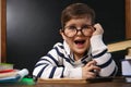 Cute child wearing glasses at desk in classroom. First time at school Royalty Free Stock Photo