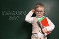 Cute little child wearing glasses near chalkboard with text Royalty Free Stock Photo