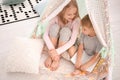 Cute little children with book sitting in hovel at home