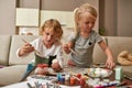 Cute little children, brother and sister painting colorful Easter eggs, sitting on a couch at home Royalty Free Stock Photo