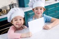 cute little children in chef hats holding blank card and smiling Royalty Free Stock Photo