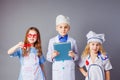 Cute little children dressed as doctors on grey background.