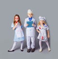 Cute little children dressed as doctors on grey