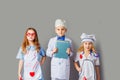 Cute little children dressed as doctors on grey