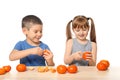 Cute little children eating citrus fruit at table on white background