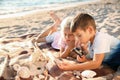 Cute little children looking at sea shells through magnifying glass on beach Royalty Free Stock Photo