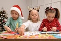 Cute little children making Christmas cards at table in decorated room Royalty Free Stock Photo