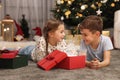 Cute little children opening gift box near Christmas tree at home Royalty Free Stock Photo