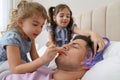 Cute little children painting face of their father while he sleeping in bed at home Royalty Free Stock Photo