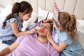 Cute little children painting face of their father while he sleeping in bed at home Royalty Free Stock Photo