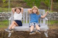 Cute little children playing outdoors. Portrait of two happy young kids swinging in garden wooden swing at the summer Royalty Free Stock Photo