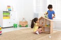 Cute little children playing with toys near wooden house on floor at home Royalty Free Stock Photo