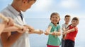 Cute little children playing tug of war game near river on sunny day Royalty Free Stock Photo