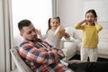 Cute little children popping paper near father while he sleeping at home