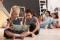 Cute little children reading book on floor in kindergarten. Indoor activity Royalty Free Stock Photo