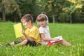 Cute little children reading books and listening to music in park on summer day Royalty Free Stock Photo