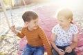 Cute little children ride on a pink wicker swing. Cheerful boy and girl are smiling at each other Royalty Free Stock Photo