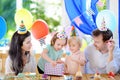 Cute little children twins and their parents having fun and celebrate birthday party with colorful decoration and cake. Royalty Free Stock Photo