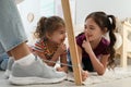 Cute little children tying shoe laces of their father together at home, closeup