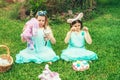 Cute little children wearing bunny ears on Easter day sitting on grass in garden. Girls holding painted eggs cover their Royalty Free Stock Photo