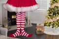 Cute little christmas elf girl wearing striped stockings standing in a decorated christmas living room with gifts and christmas Royalty Free Stock Photo