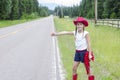 Cute little cowgirl trying to hitch hike a ride on a lonely road Royalty Free Stock Photo