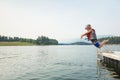 Cute little daring boy jumping off the boat dock at the lake. Being adventurous