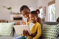 Cute little daughter and african mother using digital tablet to do a video call Royalty Free Stock Photo