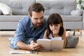 Cute little daughter listening to dad reading book at home