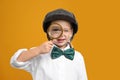 Cute little detective with magnifying glass on yellow background